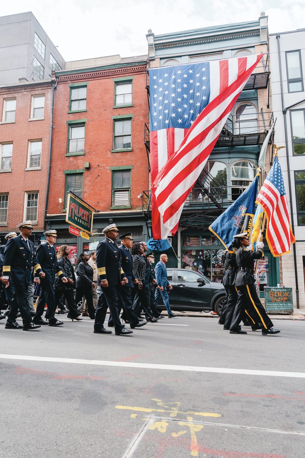 City leadership and first responders marching beneath an American flag