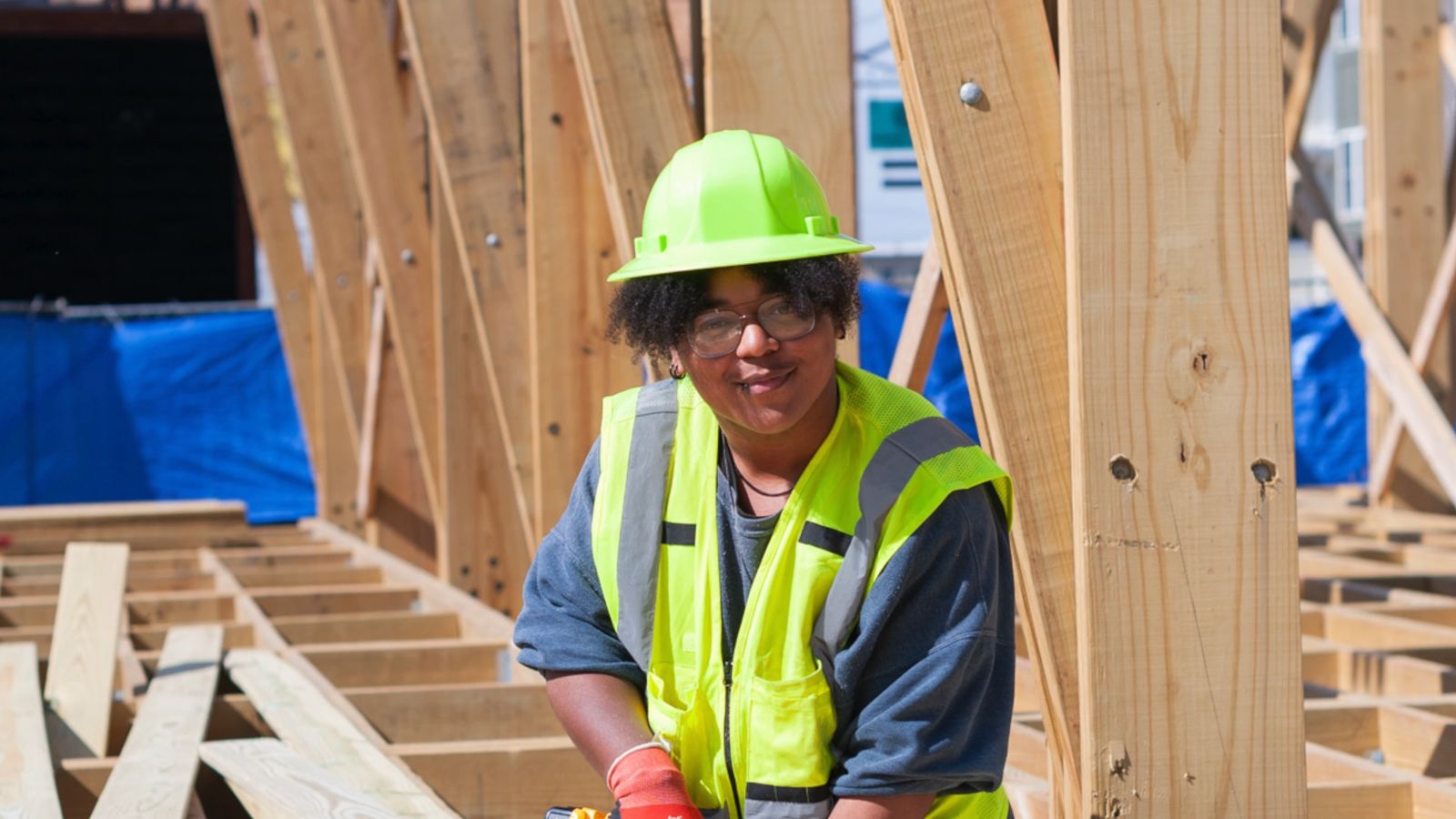 A YouthBuild student on a construction site in a hard hat and safety vest